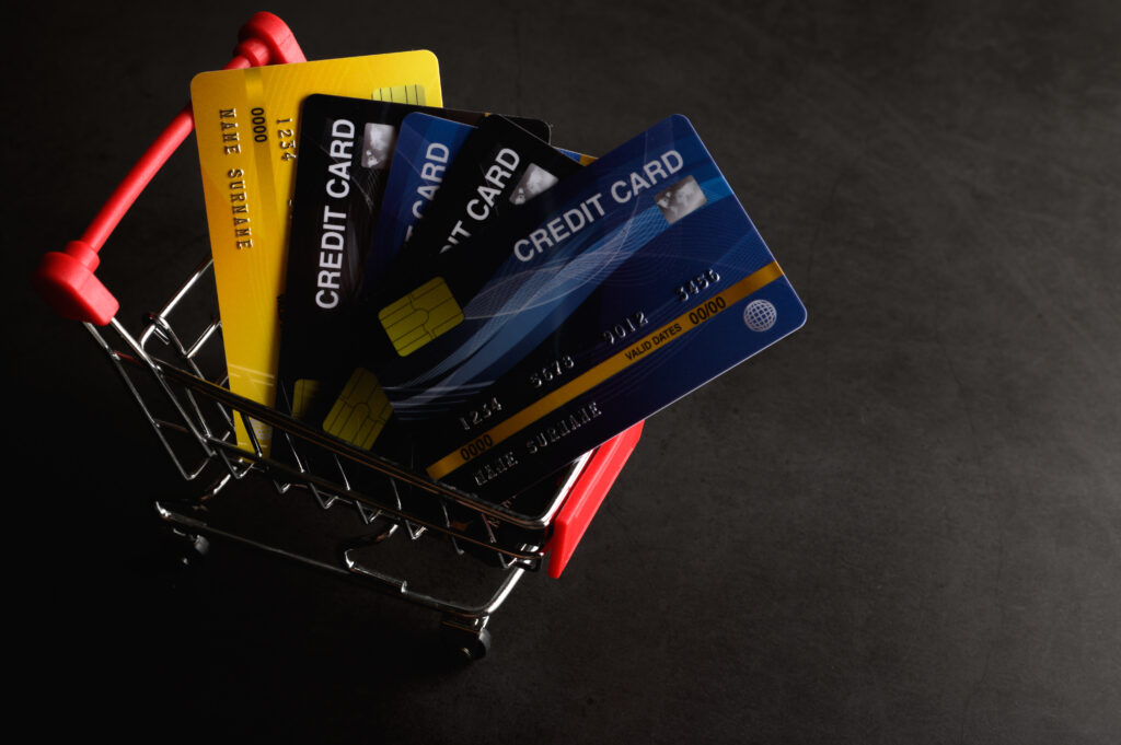 A miniature shopping cart filled with several credit cards, representing the variety of supported BigCommerce Payment Gateways.